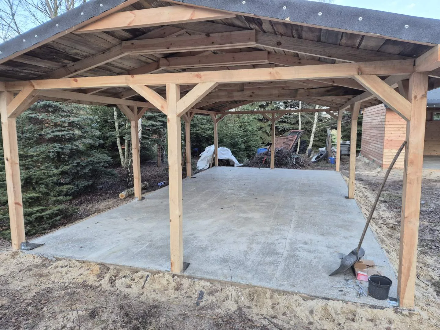 Zdjęcie przedstawia drewniany garaż w trakcie prac remontowych lub budowlanych