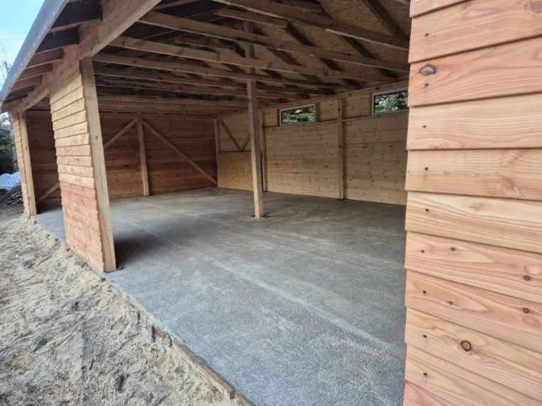 Nowy drewniany budynek gospodarczy z wyłożoną betonową posadzką i oknami